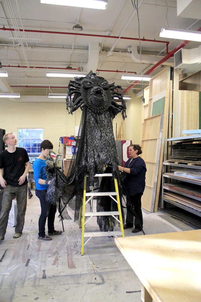 Students put finishing touches on jabberwocky puppet for production of Alice in Wonderland in Scene shop.