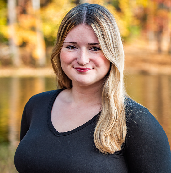 Hailey Stephens poses with yellow foliage behind her.