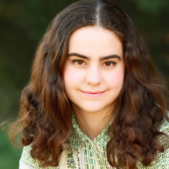 Eloise Wescott sits for a portrait in a green and white patterned shirt.